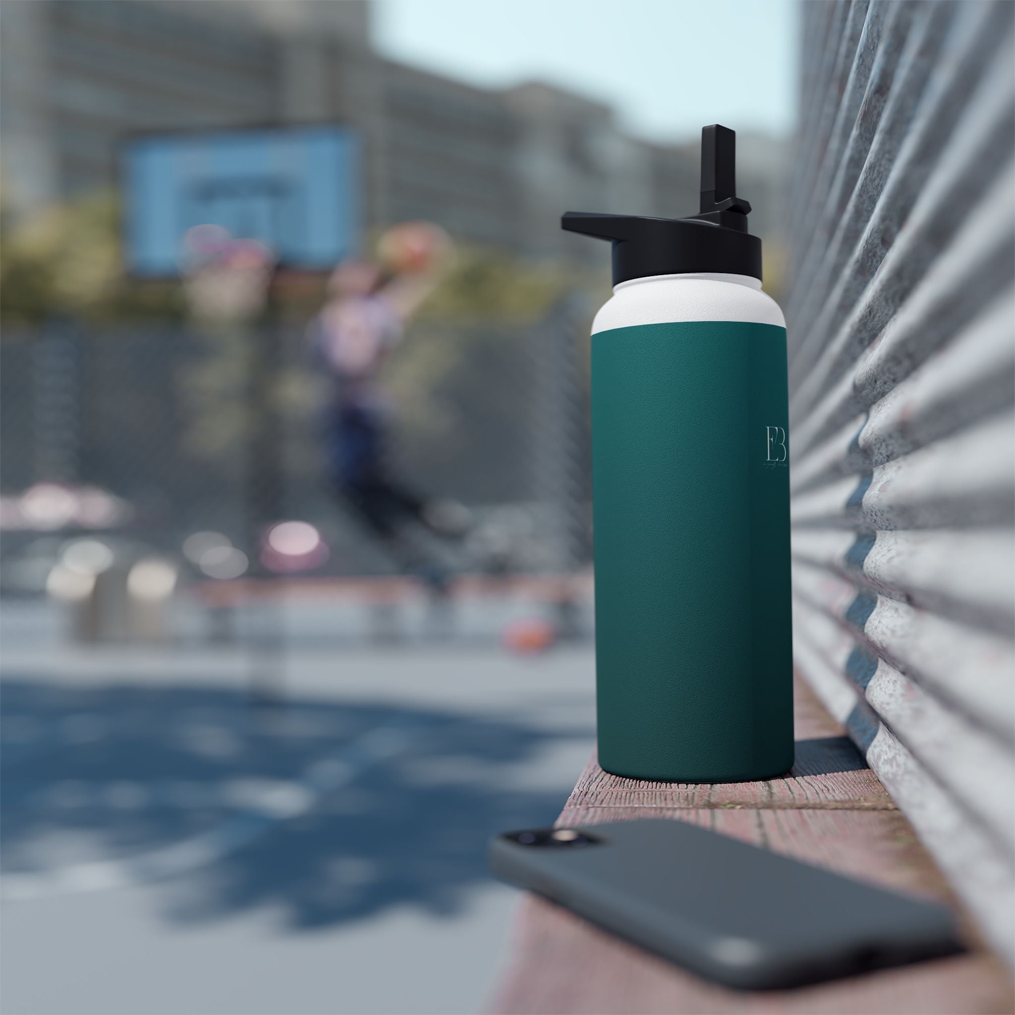 Deep teal insulated water bottle with sports lid beside yoga mat