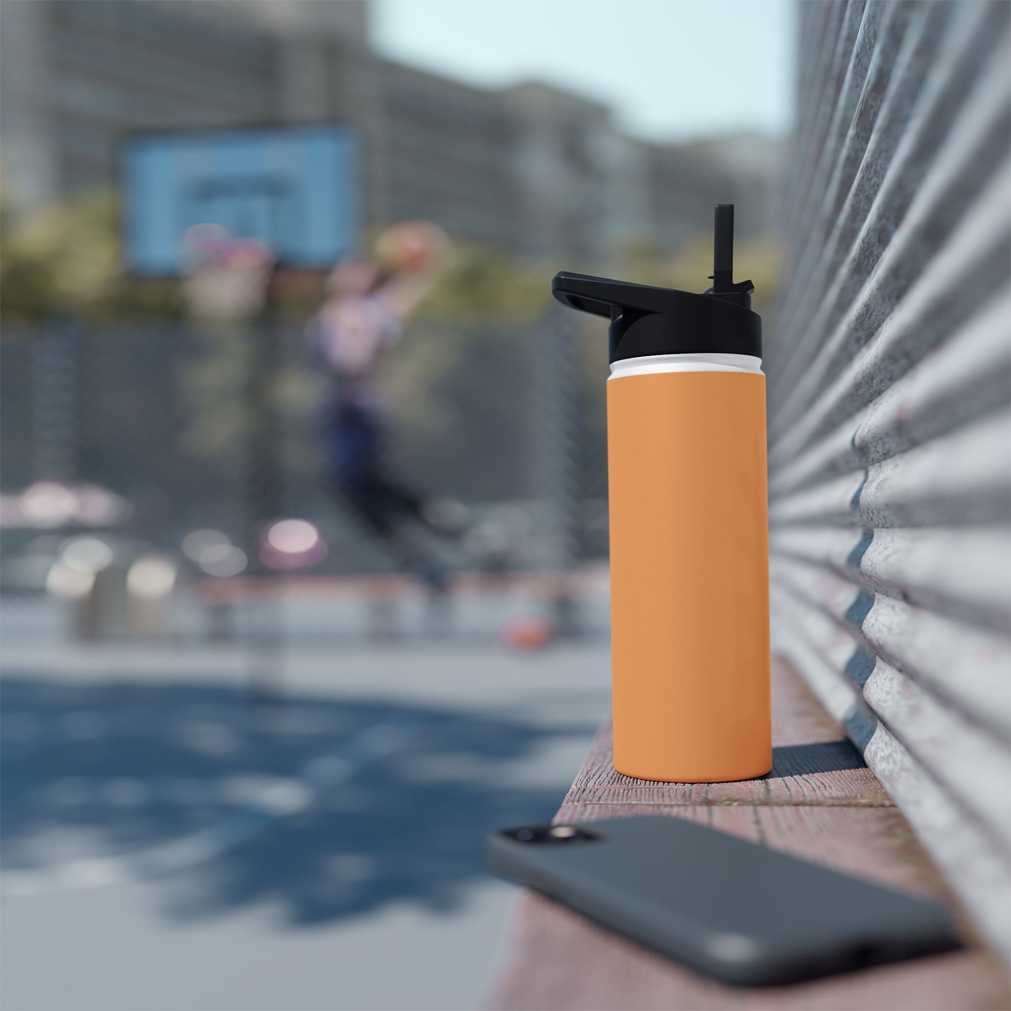 Matte orange-gold stainless water bottle with black sports lid, standing on tabletop