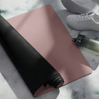 Mauve yoga mat with black rolled side and water bottle on top.