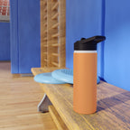 Matte orange-gold stainless water bottle with black sports lid on wooden table