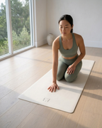 Cream natural rubber yoga mat with EB logo, person kneeling with hands down