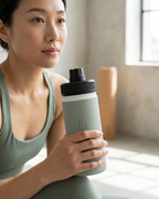 Sage insulated water bottle with black lid held in hand, embossed EB logo