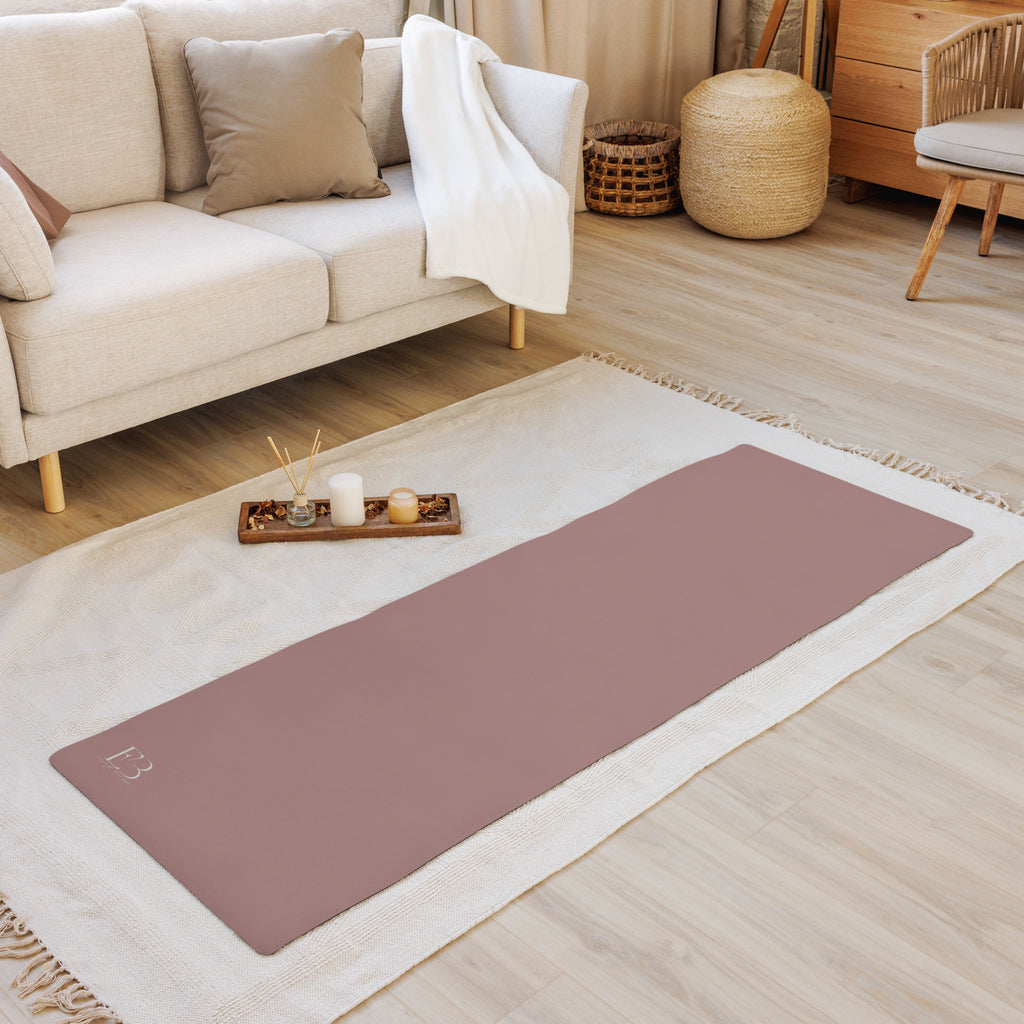 Mauve yoga mat on white rug, corner logo visible.