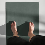 Cypress green yoga mat under bare feet, showing textured slip-resistant surface.