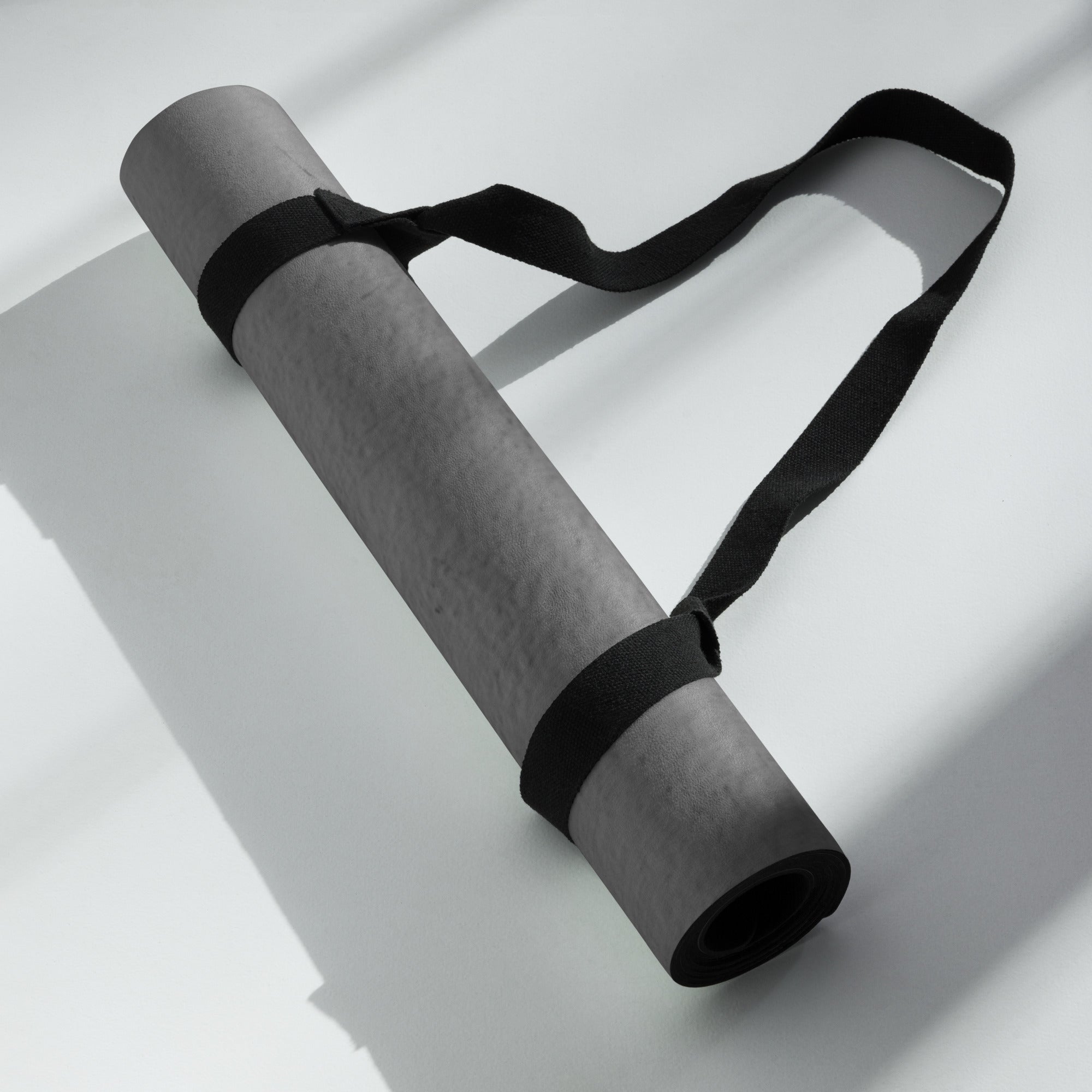 Rolled dark gray yoga mat secured with a black strap. Eco Black Dark gray natural rubber yoga mat with Suede top 