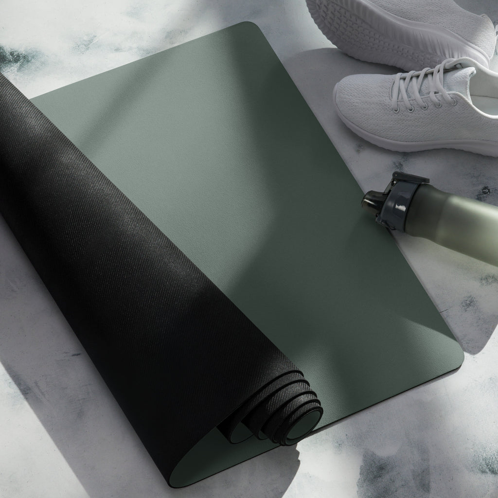 Rolled cypress green yoga mat with black edge banding and a bottle nearby.