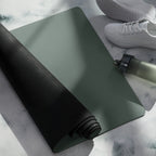 Rolled cypress green yoga mat with black edge banding and a bottle nearby.