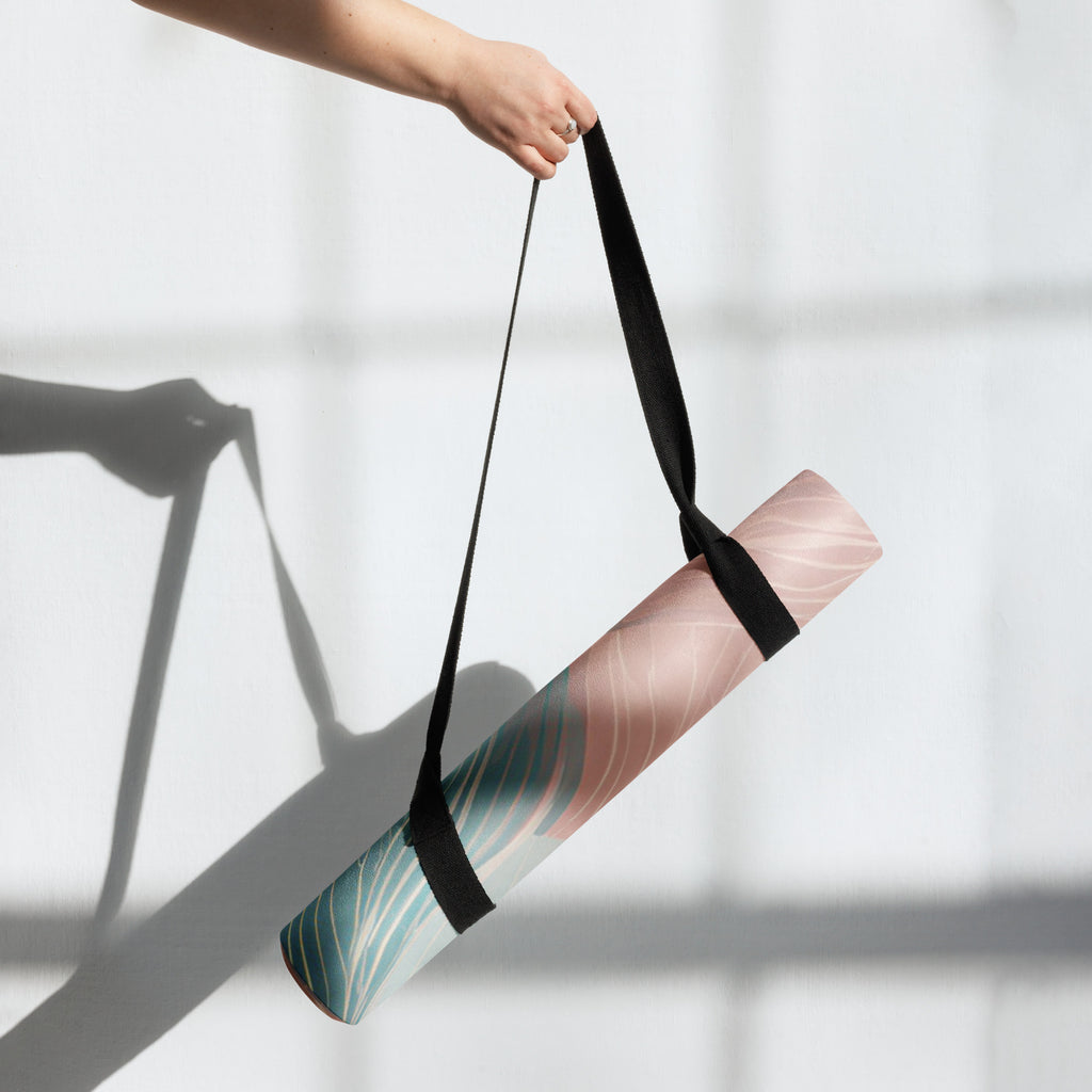Natural rubber yoga mat being carried using a black shoulder strap