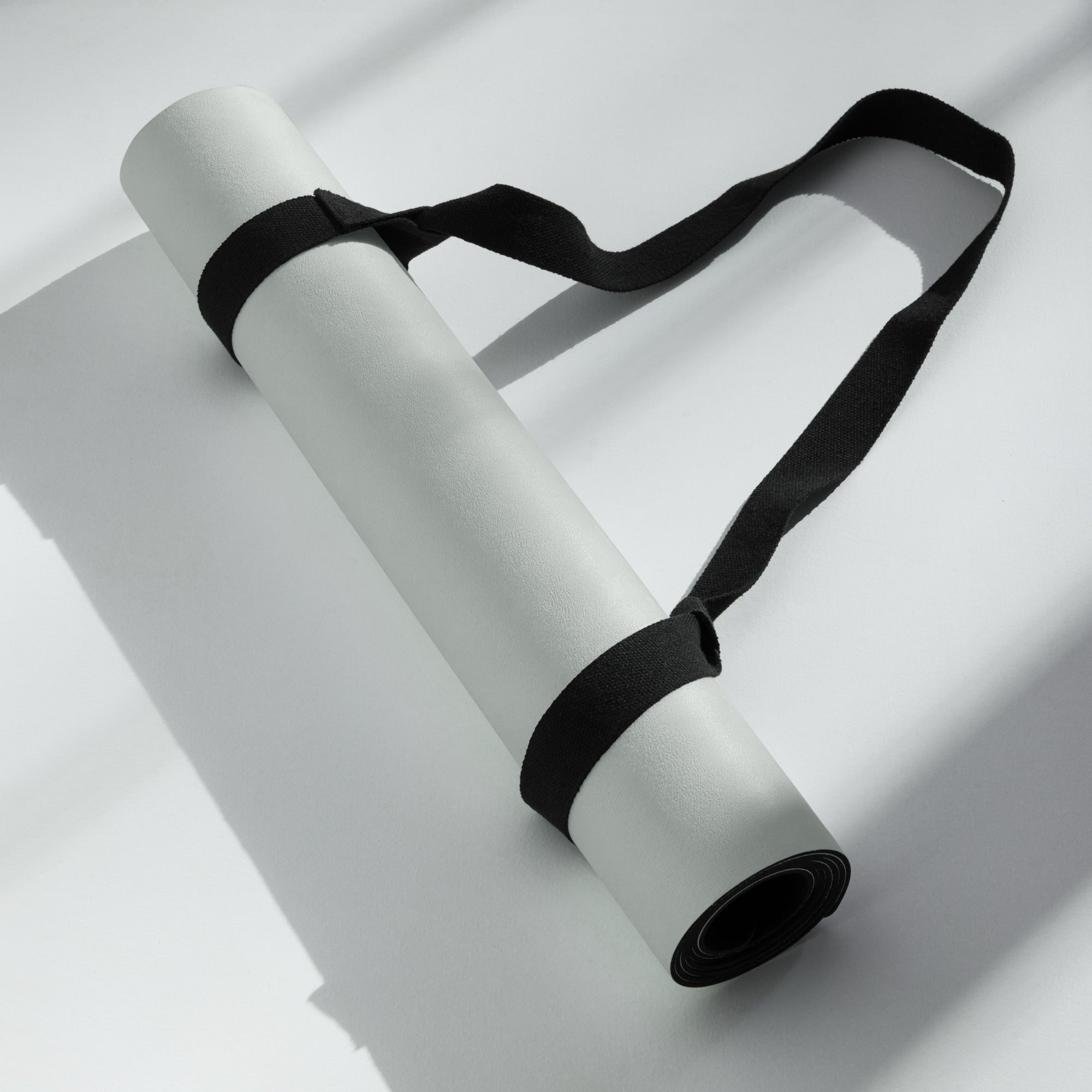 Rolled misty sage yoga mat secured with black strap, ends and grip edge visible