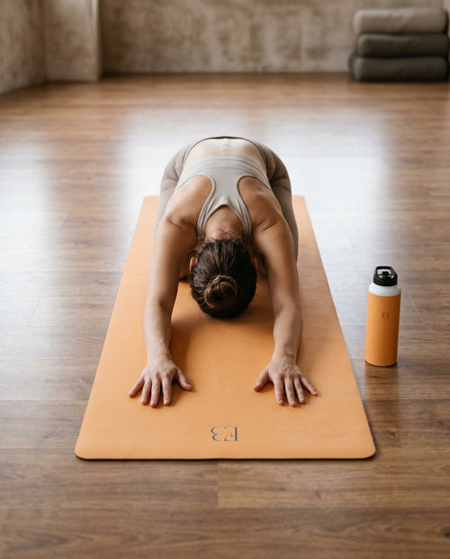 Yogi practicing Eco Black yoga on a mat with a water bottle nearby  Artisan's Gold Natural Rubber Yoga Mat | Non-Toxic & Eco-Friendly | Eco Black