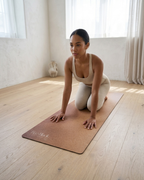 Brown natural rubber yoga mat laid flat for a kneeling yoga pose; textured surface visible.