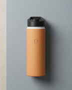 Amber insulated stainless steel water bottle on wall, black top with B3 monogram