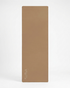 Tan yoga mat standing vertically with logo printed on the surface