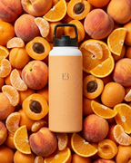 Amber insulated stainless steel water bottle with black lid and B3 logo, condensation beads