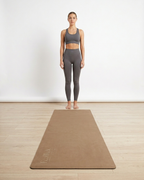 Tan natural rubber yoga mat laid flat on the floor with logo