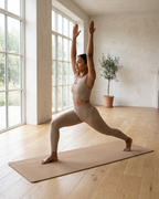 Tan natural rubber yoga mat under a standing lunge yoga pose