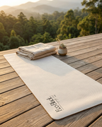 Light gray yoga mat on wooden patio, with printed logo near one end.
