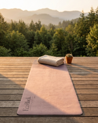 Natural rubber yoga mat in violet-pink with horizon design on wooden surface
