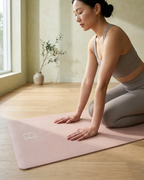 Blush yoga mat with logo at corner during seated yoga stretch