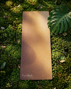 Brown EcoBlack yoga mat on green moss with logo at bottom