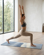 Yoga mat with blue mountain haze print under a standing lunge yoga pose indoors.