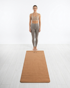 Golden yoga mat on the floor under a standing pose