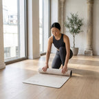Light beige yoga mat on floor as person kneels and stretches