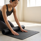 Black yoga mat in use during yoga, with hands resting on the mat surface.