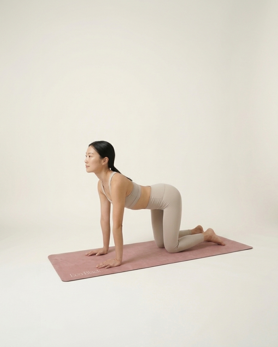 Dusty rose yoga mat beneath a hands-and-knees yoga pose, with the printed logo near one end.
