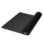 Black yoga mat unrolled with rounded edge and rolled section at the corner.