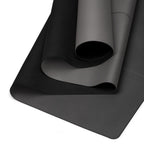 Black yoga mat with rolled section and grip texture visible along the fold.