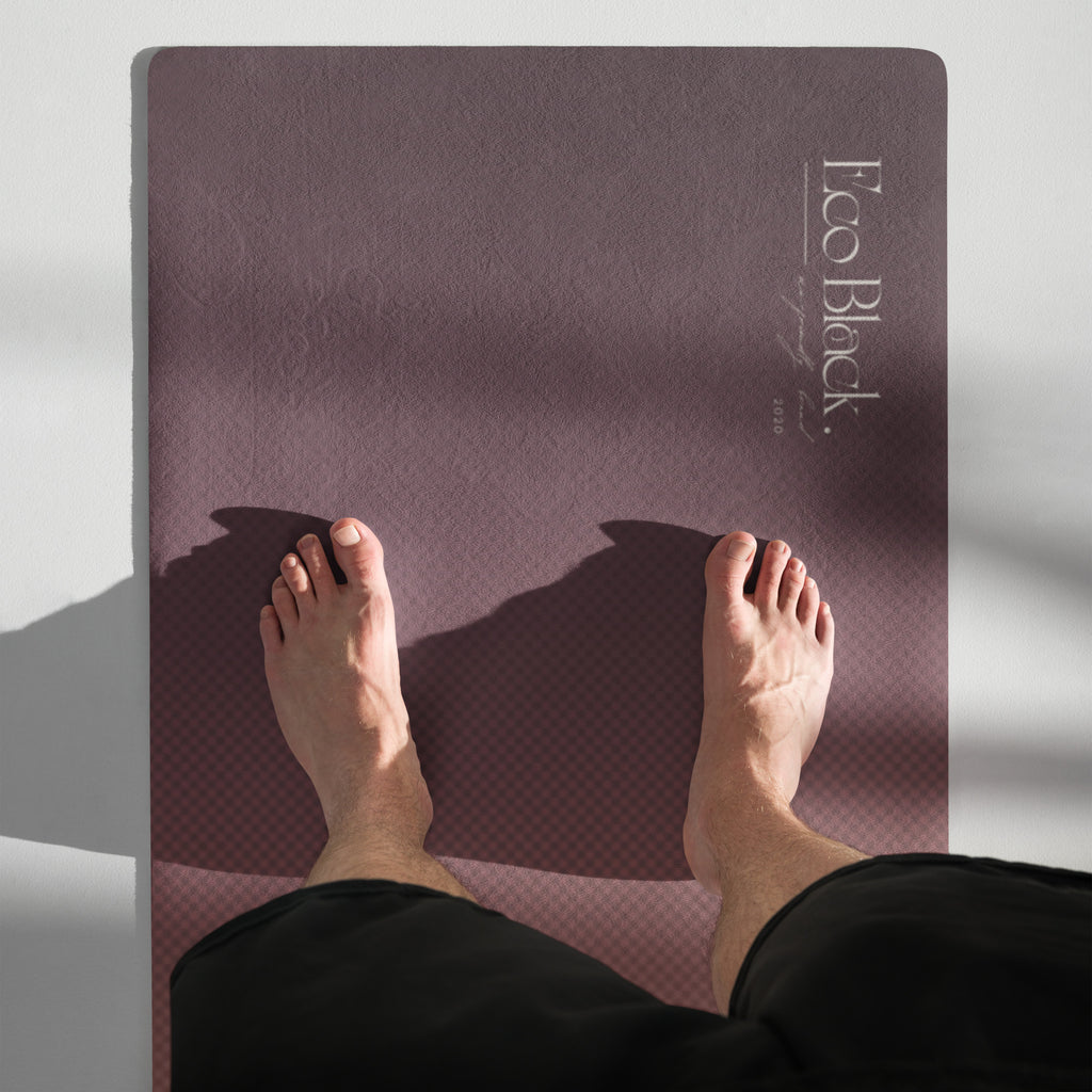 Yoga mat laid flat with mauve textured surface and small brand logo text