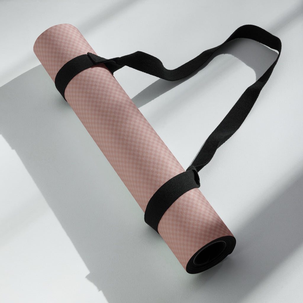 Rolled yoga mat secured with black straps, mauve textured surface visible