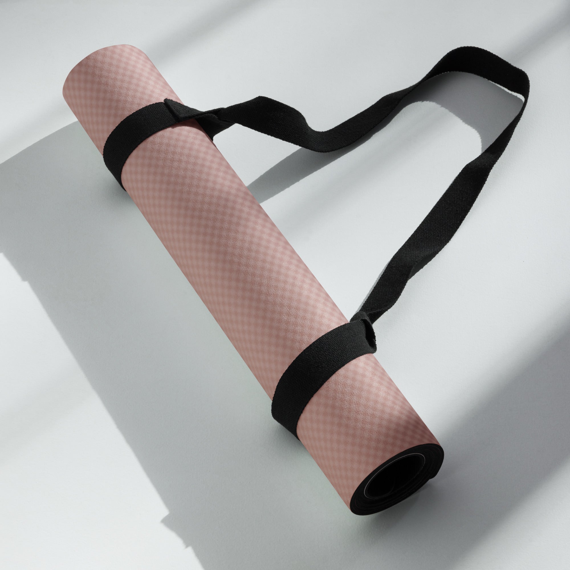 Rolled yoga mat secured with black straps, mauve textured surface visible