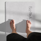 Light gray yoga mat under feet during stretching, small logo near top