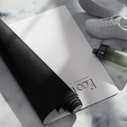 Light gray yoga mat with embossed logo, rolled edge beside darker mat