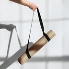 Natural rubber yoga mat with black carry strap, golden tan surface visible
