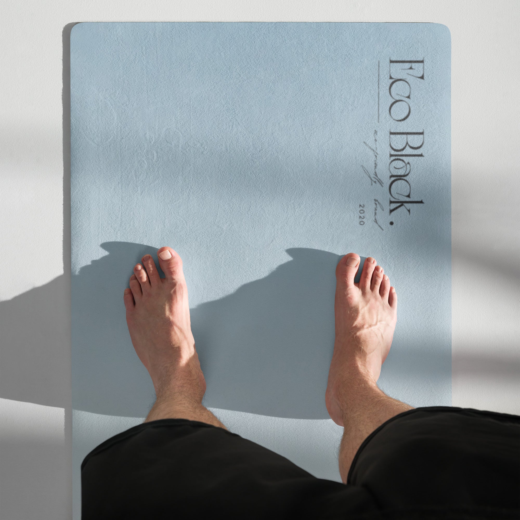 Light blue yoga mat with logo near the top edge and feet resting on it