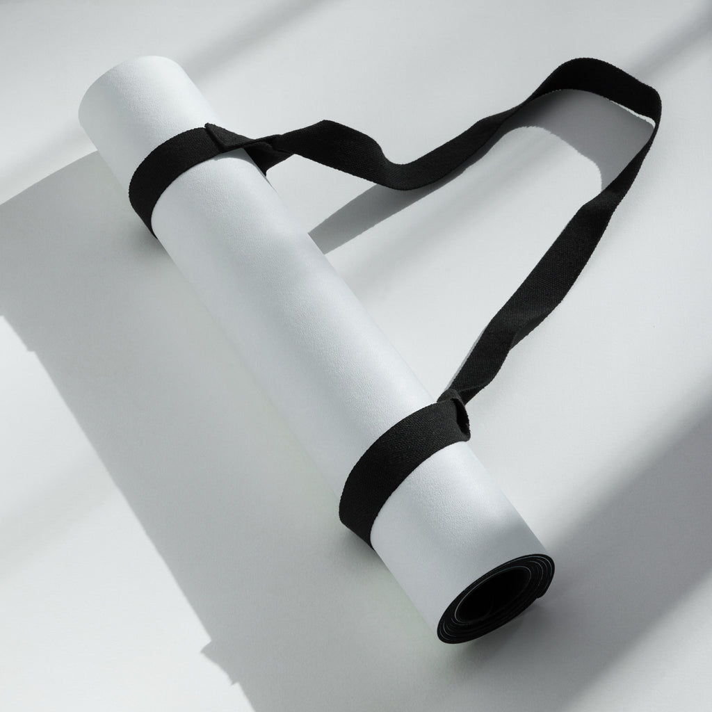 Rolled light blue yoga mat secured with black straps