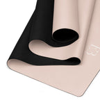 Blush yoga mat showing black textured grip underside and corner logo