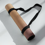 Brown natural rubber yoga mat secured with a black carrying strap, shown in folded position.