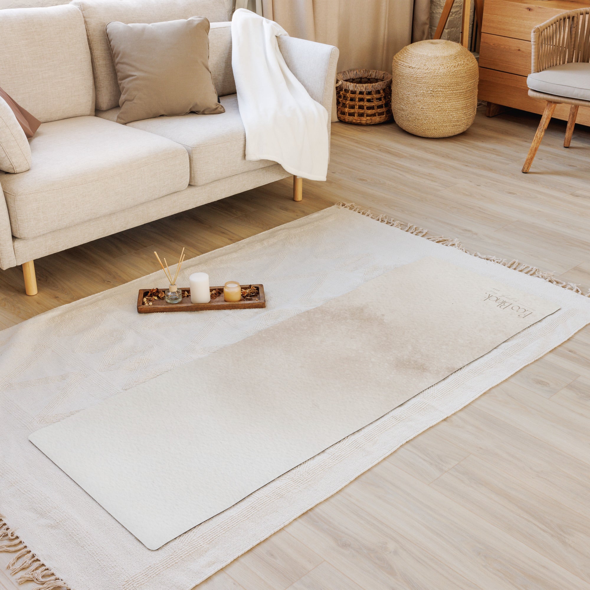 Light beige yoga mat laid flat on floor next to sofa and cushions