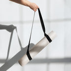 Yoga mat tied for carrying: beige mat with black strap held up