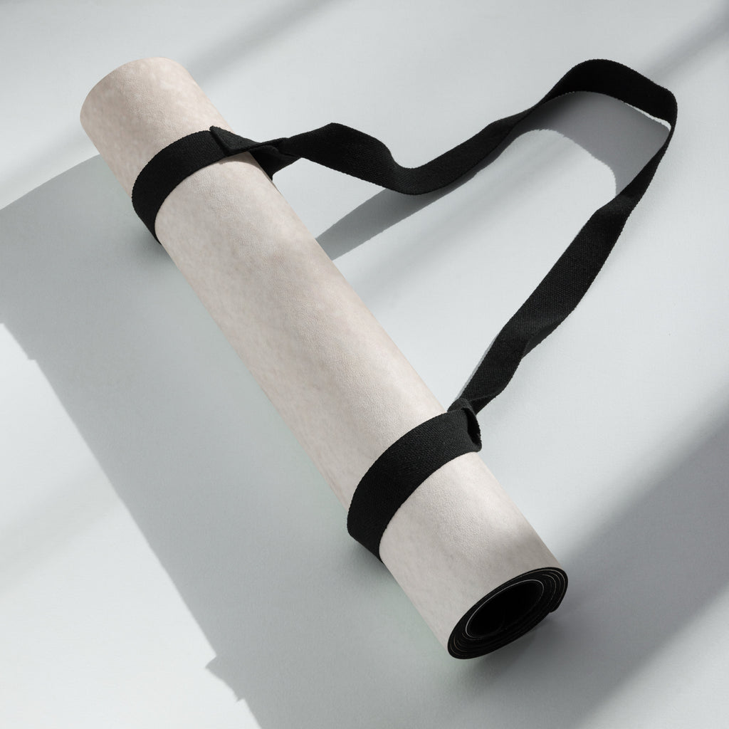 Rolled yoga mat secured with black strap, beige rubber surface visible