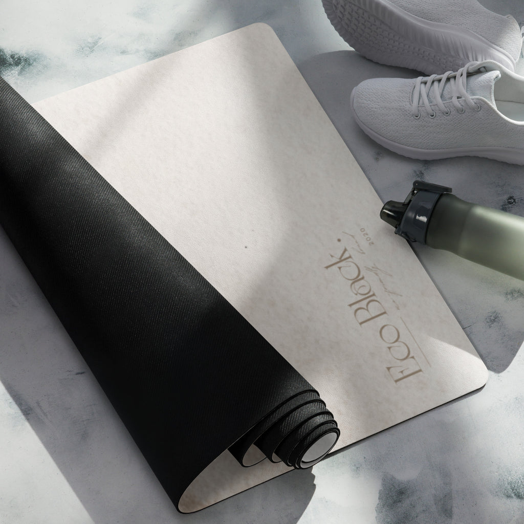 Rolled yoga mat with beige front and black back, near sneakers and water bottle