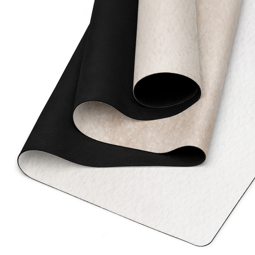 Yoga mat with black textured surface partially rolled over light surface