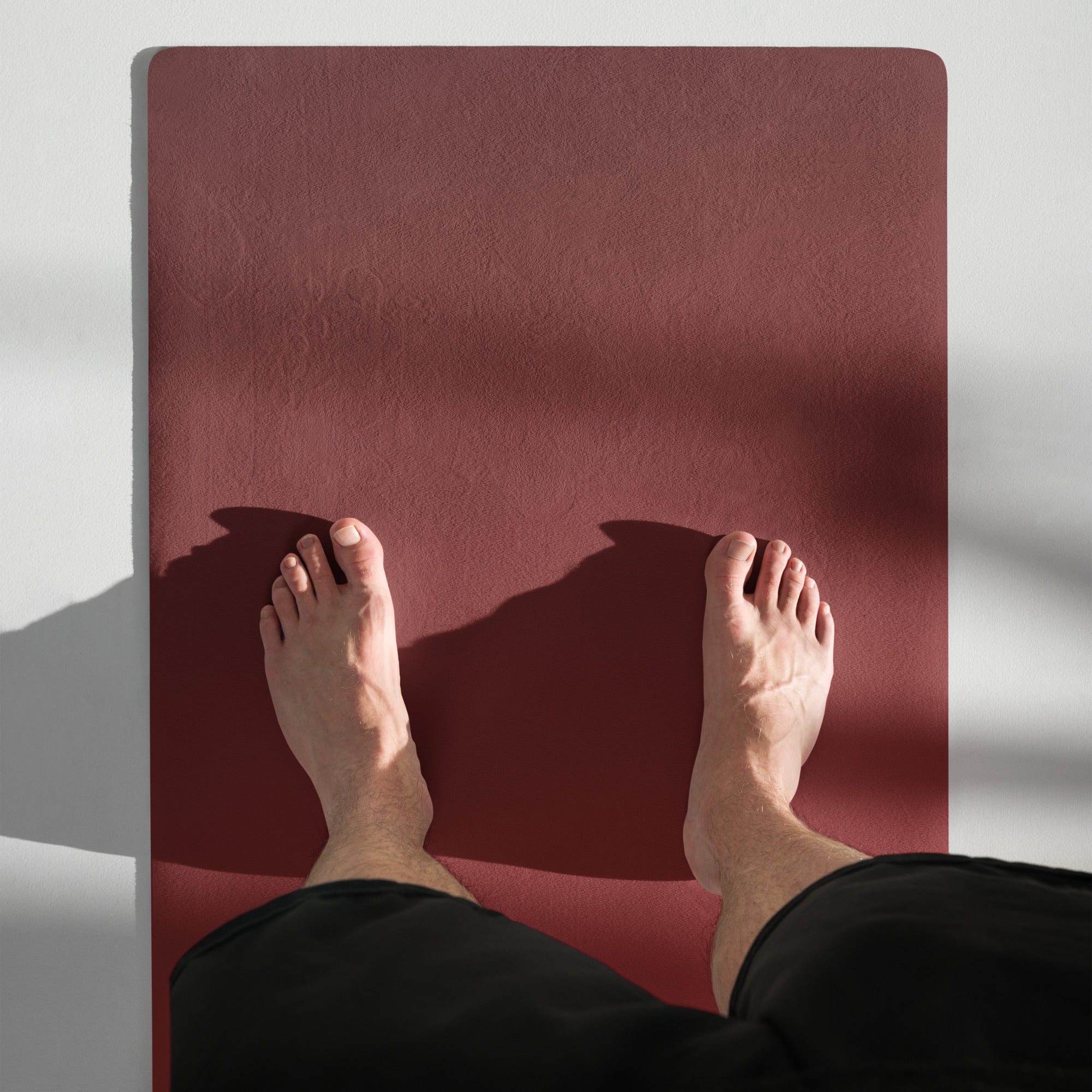 Maroon yoga mat with textured surface, hands and feet on top