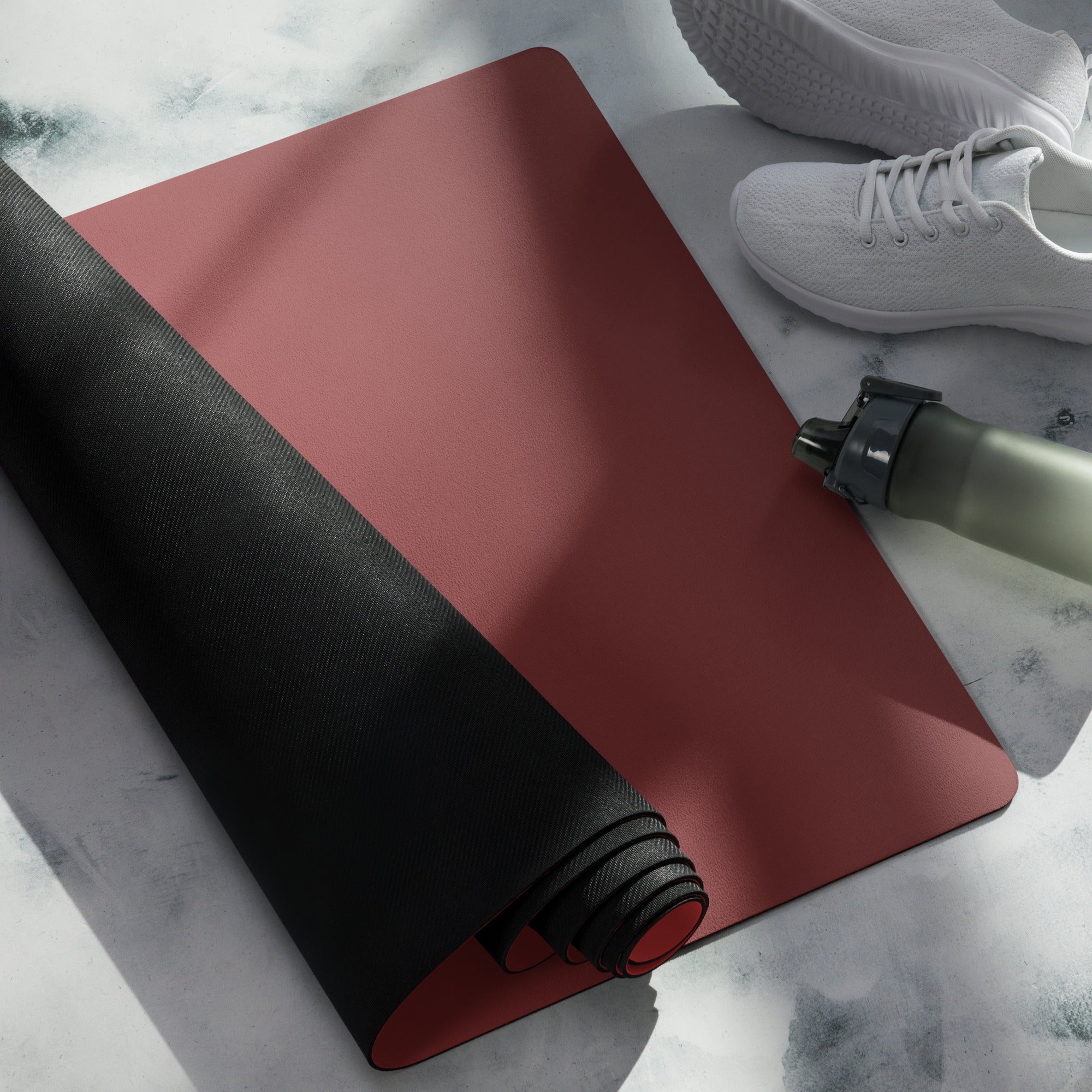 Crimson yoga mat roll with black underside edge beside another roll