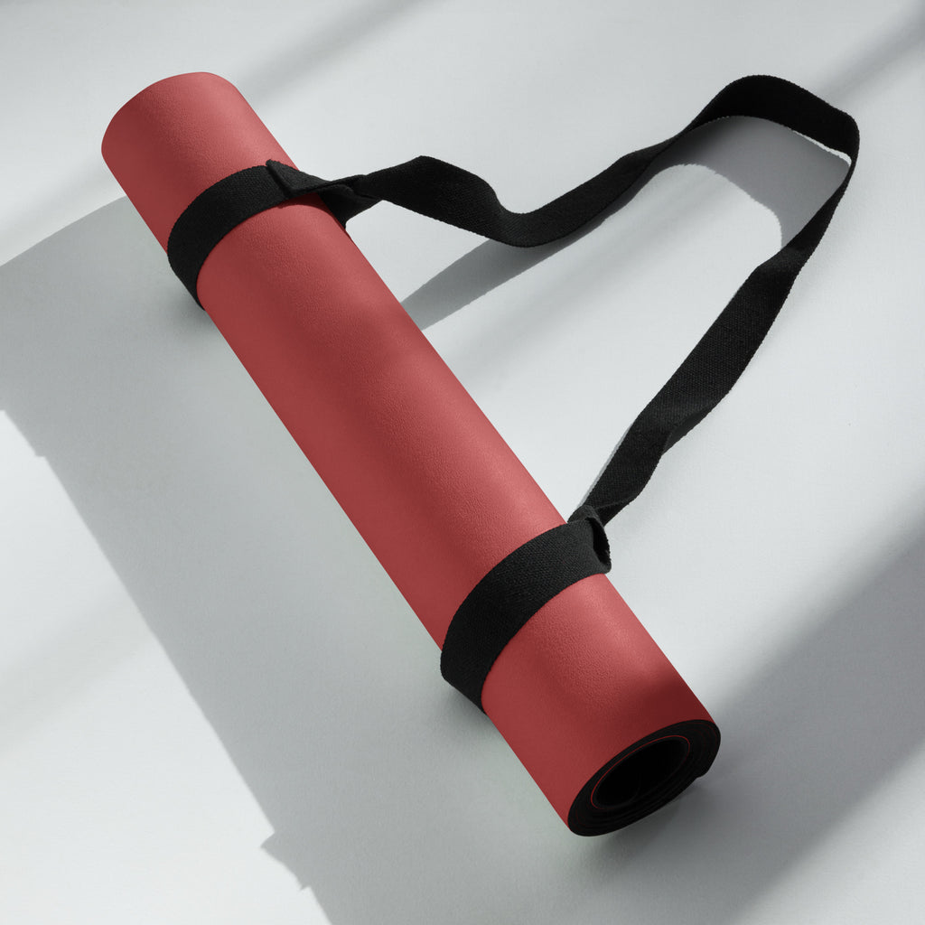 Red yoga mat rolled with a black carrying strap