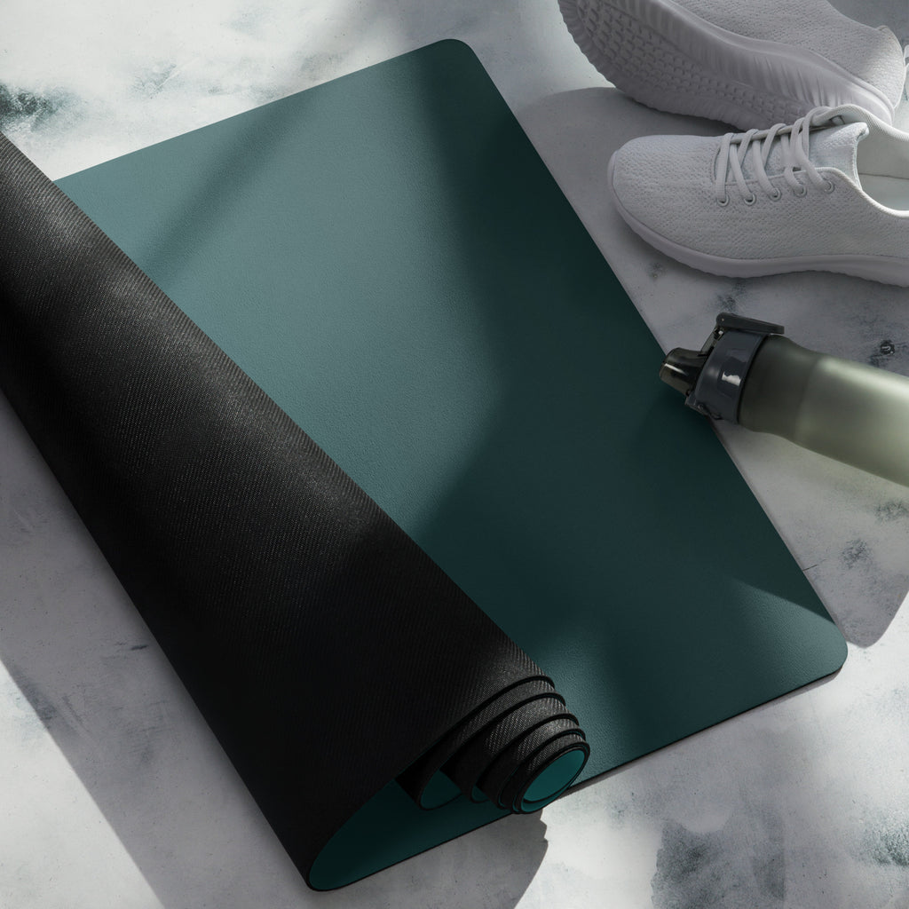 Teal natural rubber yoga mat rolled and folded with black grip strap detail